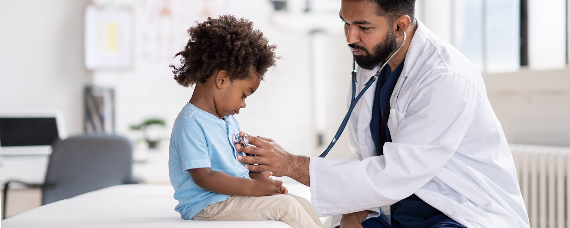 A doctor places a stethoscope on a child's chest.