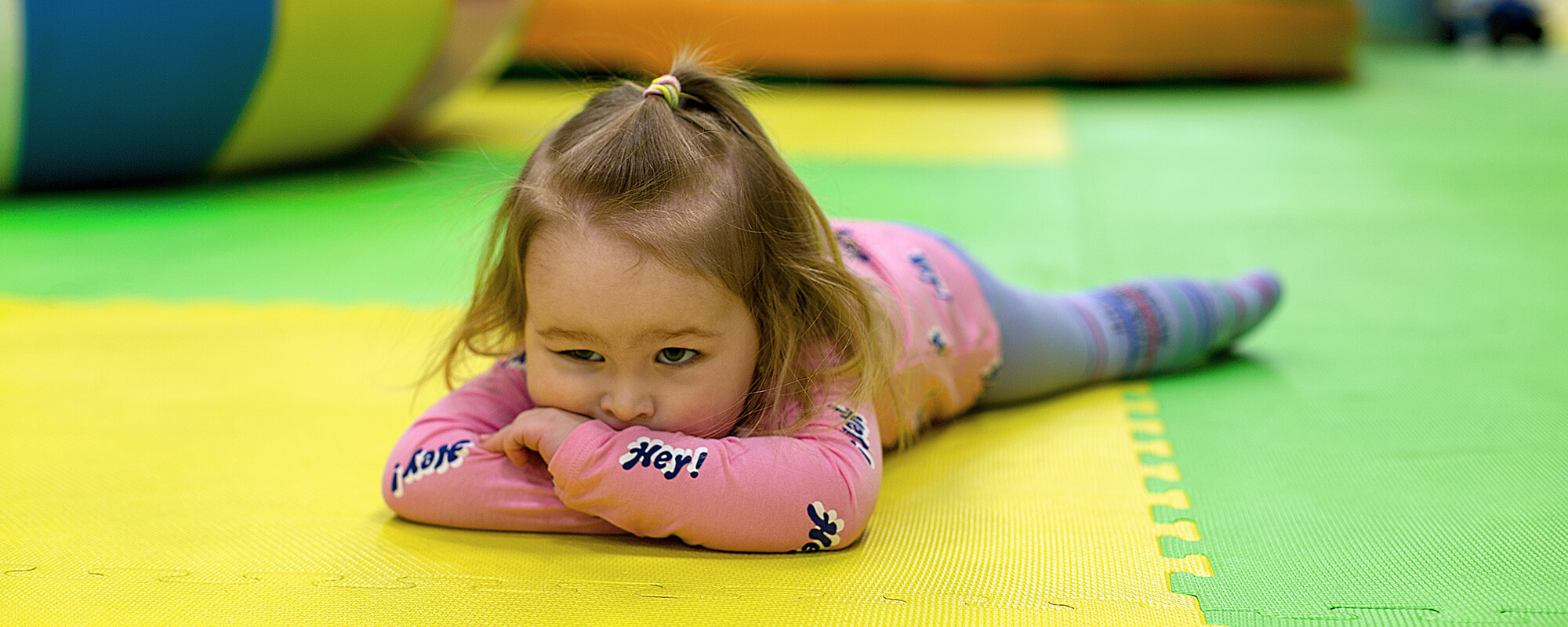 A little girl lays bored on the floor.